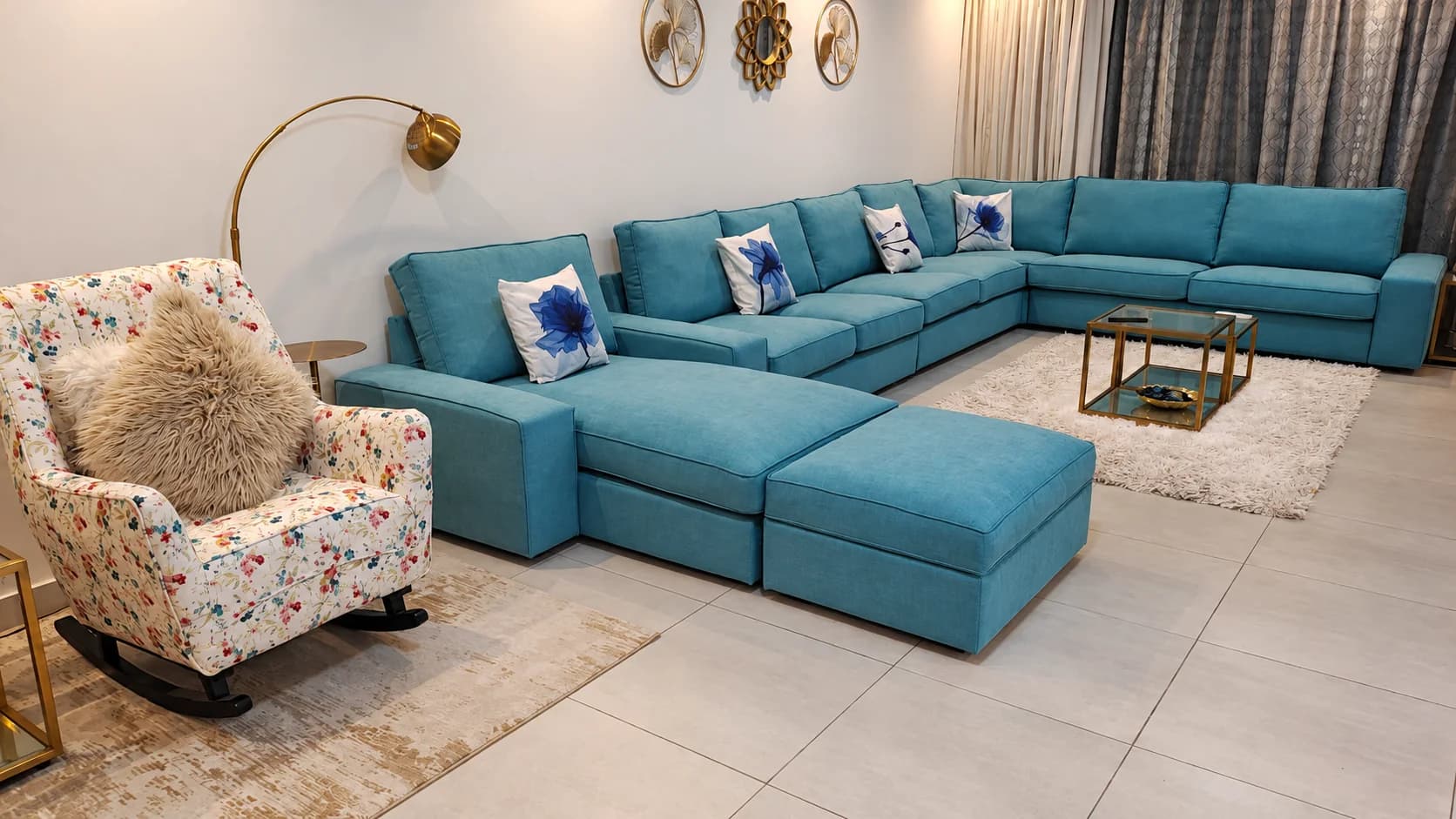 A teal corner sofa and a floral rocking chair