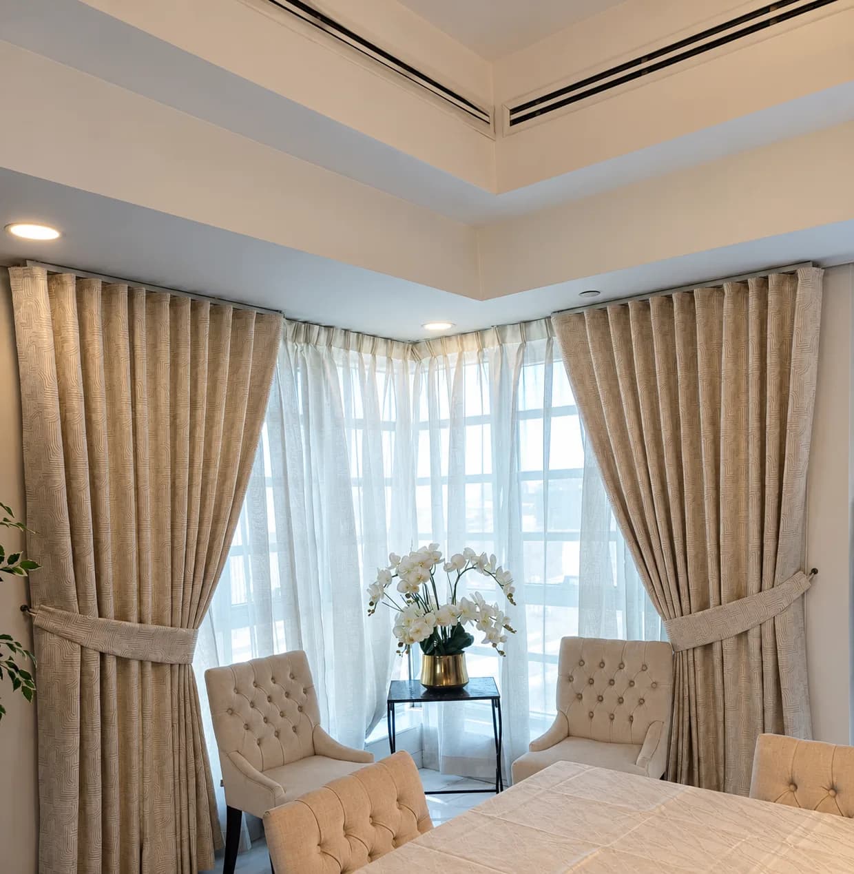 Wave curtains with tiebacks and sheers on a ceiling track that turns a corner window
